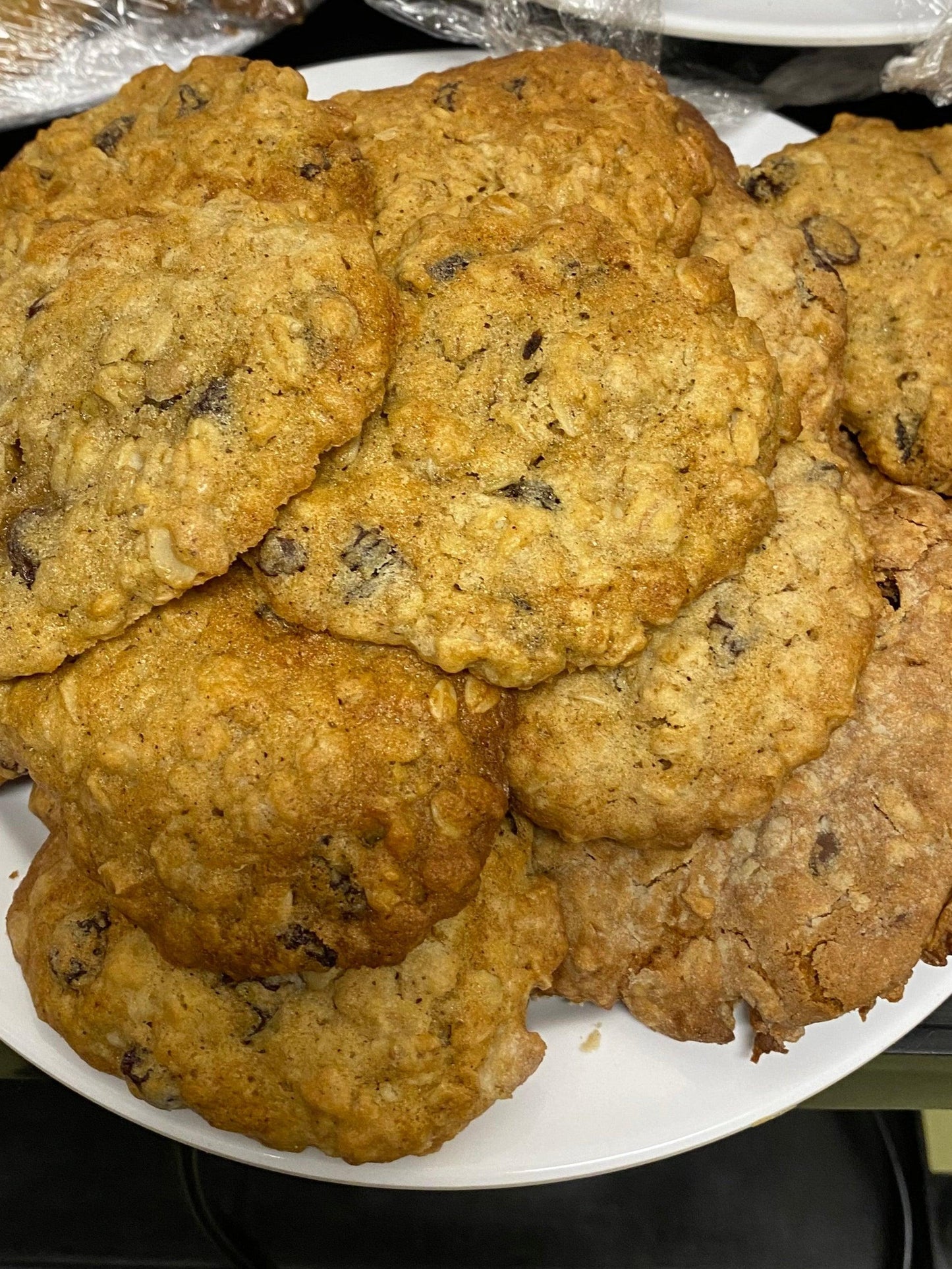 A white plate stacked high with freshly baked oatmeal raisin cookies, arranged casually and invitingly.