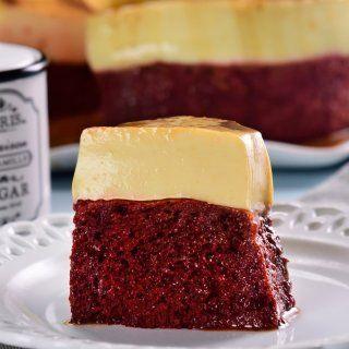 A slice of red velvet cake layered with creamy vanilla frosting, served on a white plate with soft lighting, highlighting its rich textures.