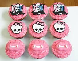 A grid of pink cupcakes featuring skull designs and bows, topped with colorful Monster High decorations.
