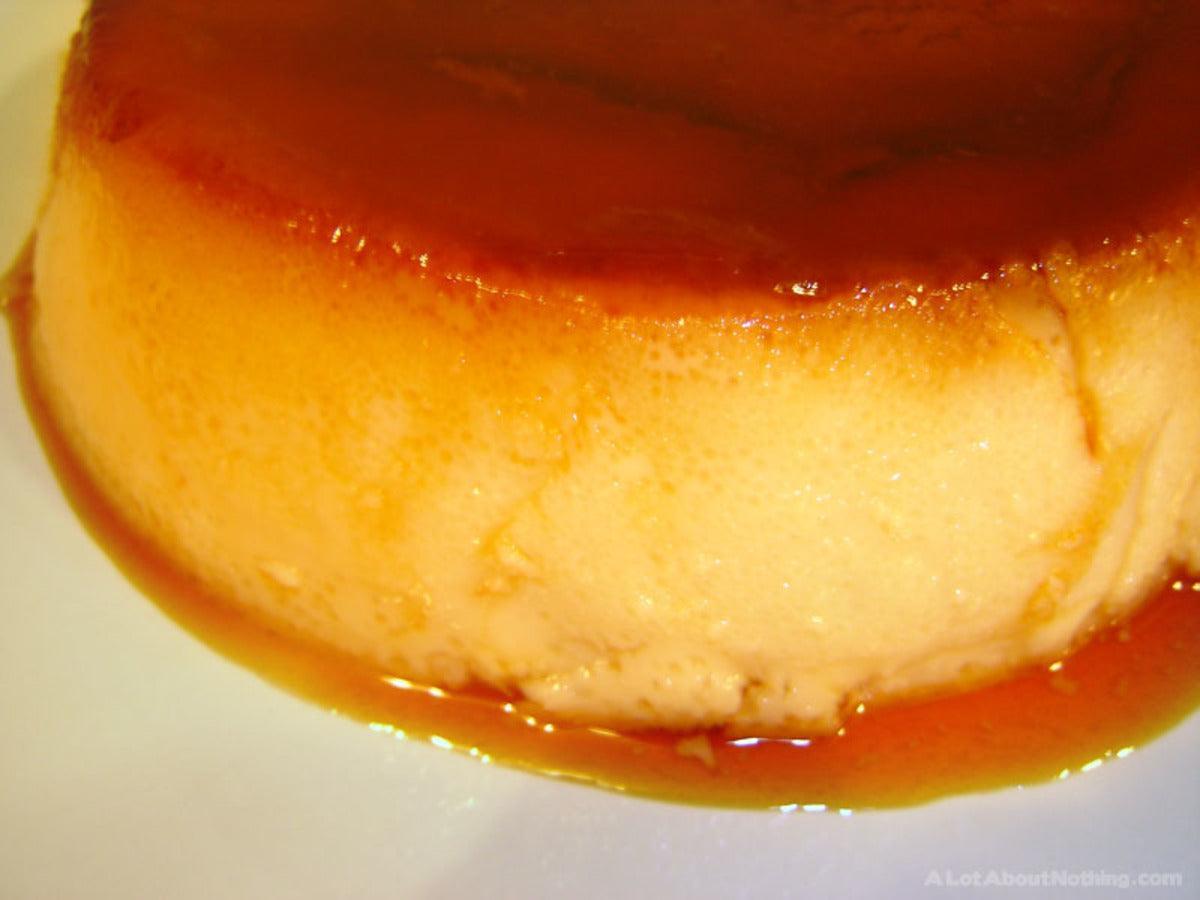 A close-up of a creamy caramel flan, featuring a smooth surface glistening with golden caramel sauce.